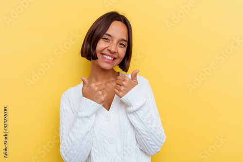 Young mixed race woman isolated on yellow background raising both thumbs up, smiling and confident.