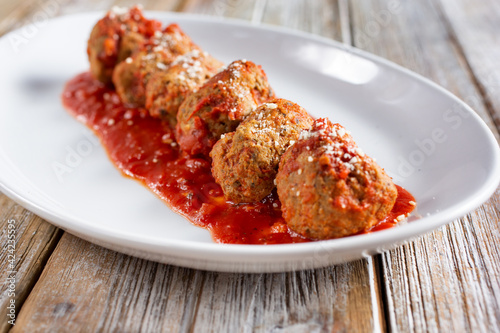 A view of a plate of meatballs with some marinara sauce.