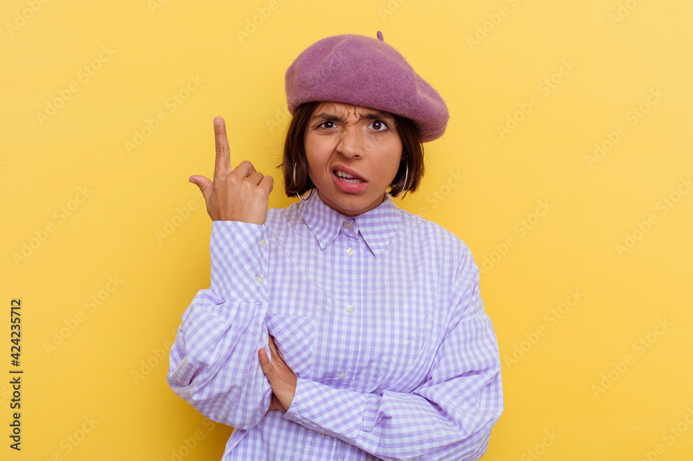 Young mixed race woman wearing a beret isolated on yellow background showing a disappointment gesture with forefinger. Young mixed race woman wearing a beret isolated on yellow background showing a disappointment gesture with forefinger.
