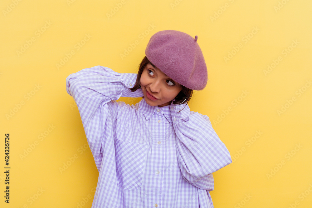 Young mixed race woman wearing a beret isolated on yellow background stretching arms, relaxed position. Young mixed race woman wearing a beret isolated on yellow background stretching arms, relaxed position.