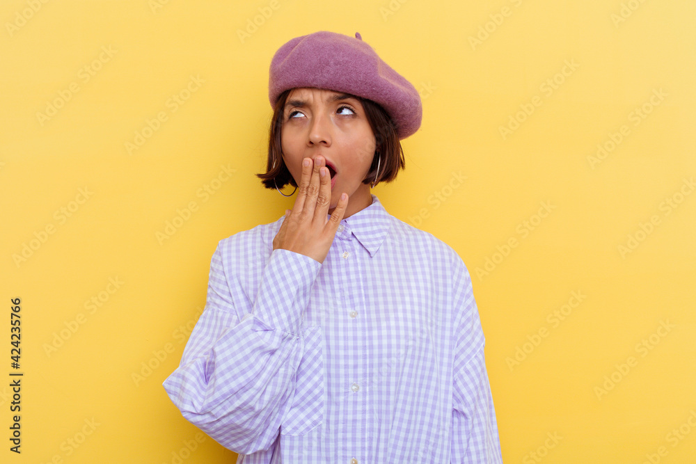 Young mixed race woman wearing a beret isolated on yellow background yawning showing a tired gesture covering mouth with hand. Young mixed race woman wearing a beret isolated on yellow background yawning showing a tired gesture covering mouth with hand.