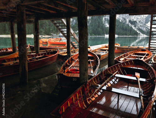 Wooden little boats under boat house on Braies lake. Comfortable view of a wet day in the mountains. Summer holidays and mountain life.