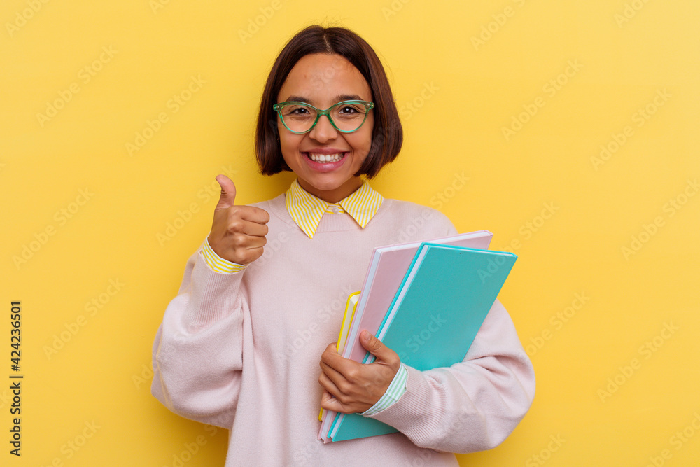 Young mixed race student woman isolated on yellow background Young mixed race student woman isolated on yellow background
