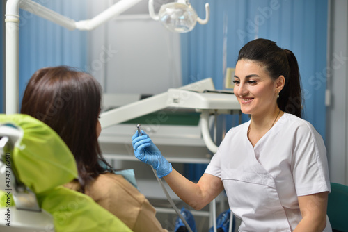 Woman dentist smiling while working with patient.