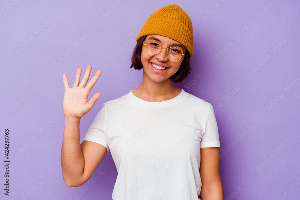Young mixed race woman wearing a wool cap isolated on purple background smiling cheerful showing number five with fingers.