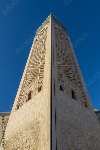 Minaret of a Hassan II mosque in Casablanca, Morocco against blue sky background. Islamic culture. Low angle view