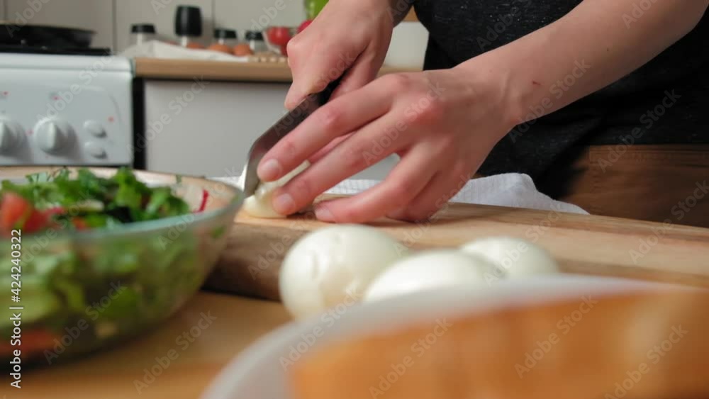 a cook in a bright kitchen cuts boiled eggs into wedges for salad. Female hands in a light kitchen cuts boiled eggs into wedges for salad. Close-up in slow motion, colorful a cook in a bright kitchen cuts boiled eggs into wedges for salad. Female hands in a light kitchen cuts boiled eggs into wedges for salad. Close-up in slow motion, colorful