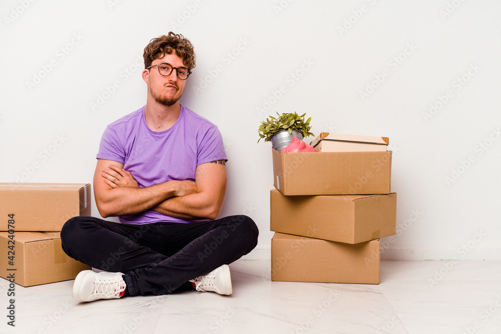 Young caucasian man sitting on the floor ready for moving isolated on white background unhappy looking in camera with sarcastic expression. Young caucasian man sitting on the floor ready for moving isolated on white background unhappy looking in camera with sarcastic expression.