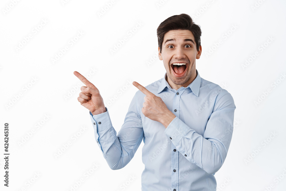 Excited ceo corporate man, manager pointing aside at promo text, showing left banner and smiling amazed, standing over white background Excited ceo corporate man, manager pointing aside at promo text, showing left banner and smiling amazed, standing over white background