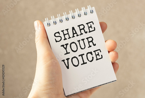 Hand show Share Your Voice text written on small whiteboard isolated on white background