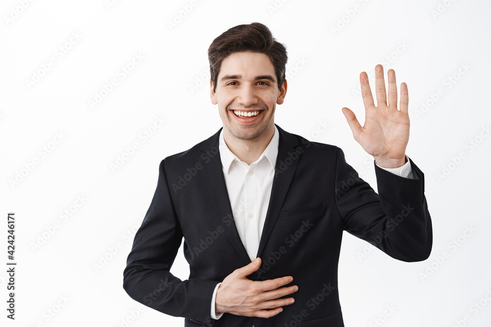 Handsome businessman in suit, corporate man waving hand and say hello, greet you, introduce himself on party, wearing formal clothes, standing over white background Handsome businessman in suit, corporate man waving hand and say hello, greet you, introduce himself on party, wearing formal clothes, standing over white background