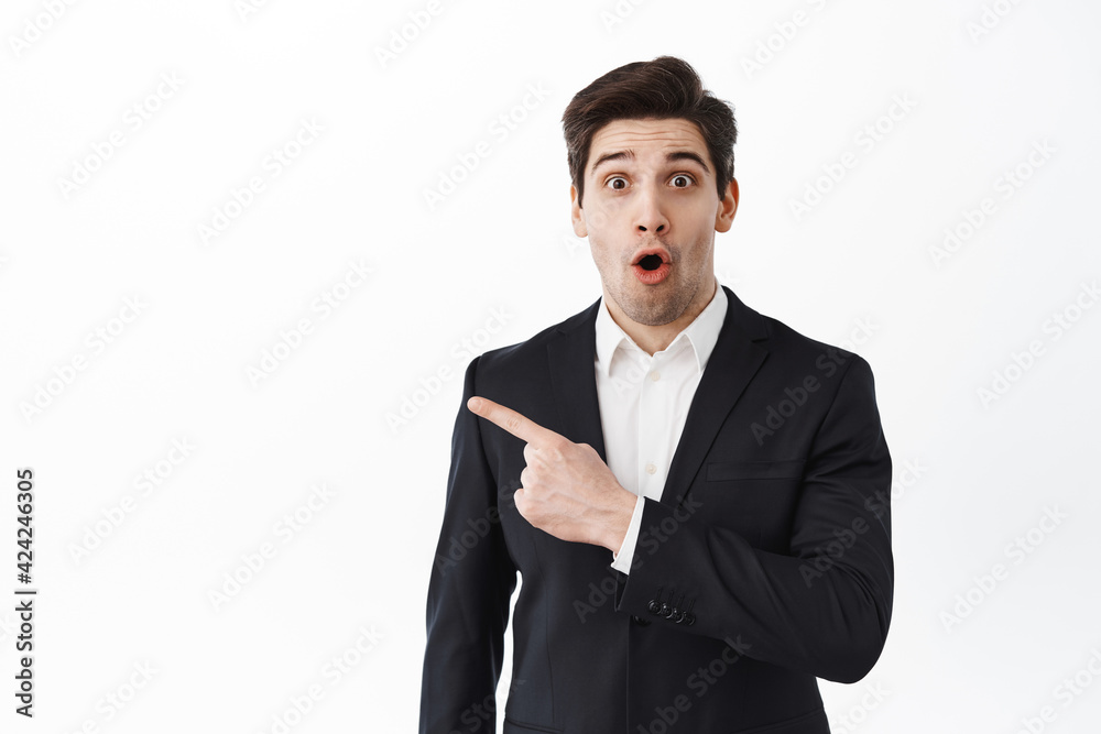 Surprised real estate agent, entrepreneur corporate man make wow face, look  intrigued and amazed, pointing aside at logo, show banner, standing over  white background Stock Photo | Adobe Stock
