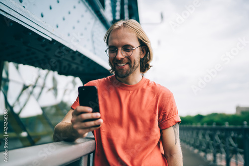 Happy hipster texting on smartphone in street