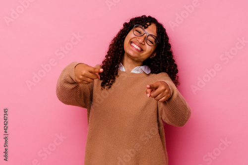 Young mixed race woman isolated on pink background cheerful smiles pointing to front. © Asier