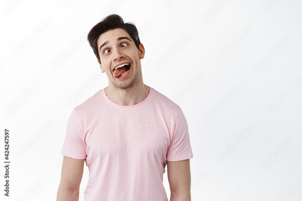 Funny man showing grimaces and tongue, making fun faces playfully, fool around, standing against white background Funny man showing grimaces and tongue, making fun faces playfully, fool around, standing against white background