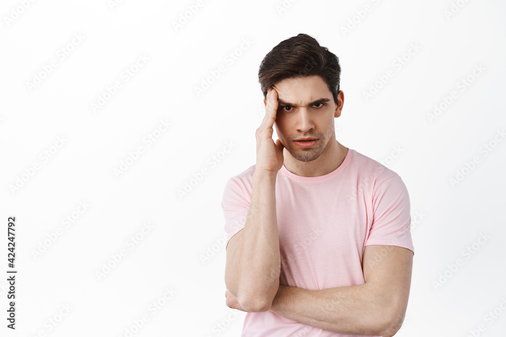 Annoyed confused man frowning, staring irratated at camera, cant understand something, standing bothered against white background Annoyed confused man frowning, staring irratated at camera, cant understand something, standing bothered against white background