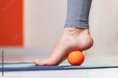 Myofascial relaxation of the muscles of the foot with a massage ball on a mat at home  close-up. Concept on the topic of preventing foot fatigue after wearing high-heeled shoes