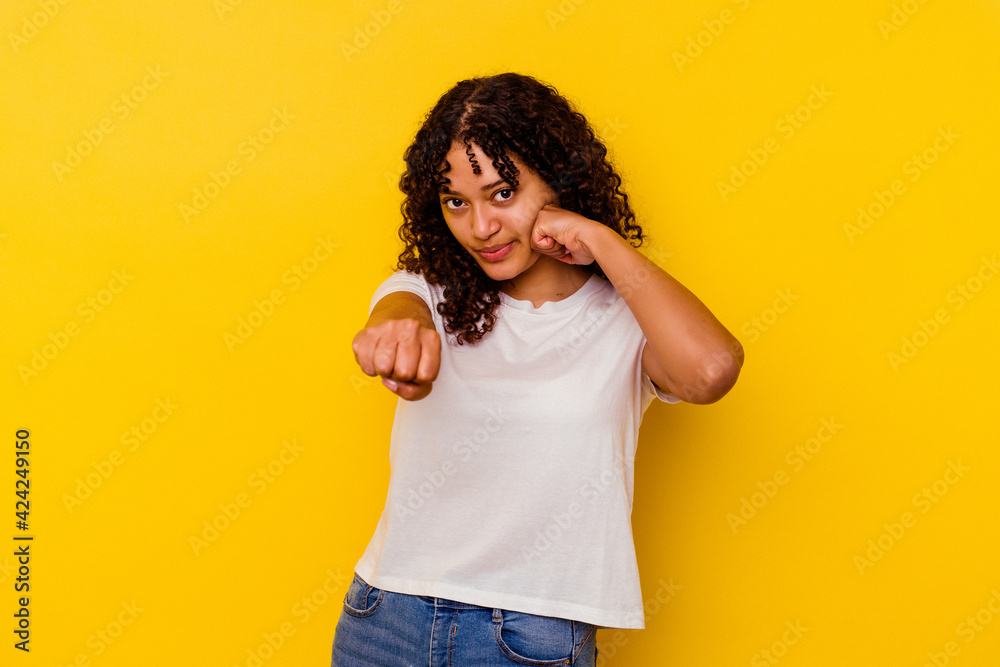 Young mixed race woman isolated on yellow background throwing a punch, anger, fighting due to an argument, boxing. Young mixed race woman isolated on yellow background throwing a punch, anger, fighting due to an argument, boxing.