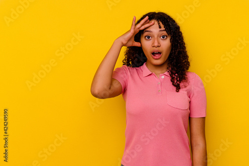 Young mixed race woman isolated on yellow background looking far away keeping hand on forehead. © Asier