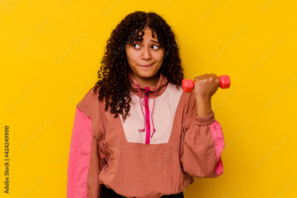 Young mixed race sport woman isolated on yellow background Young mixed race sport woman isolated on yellow background