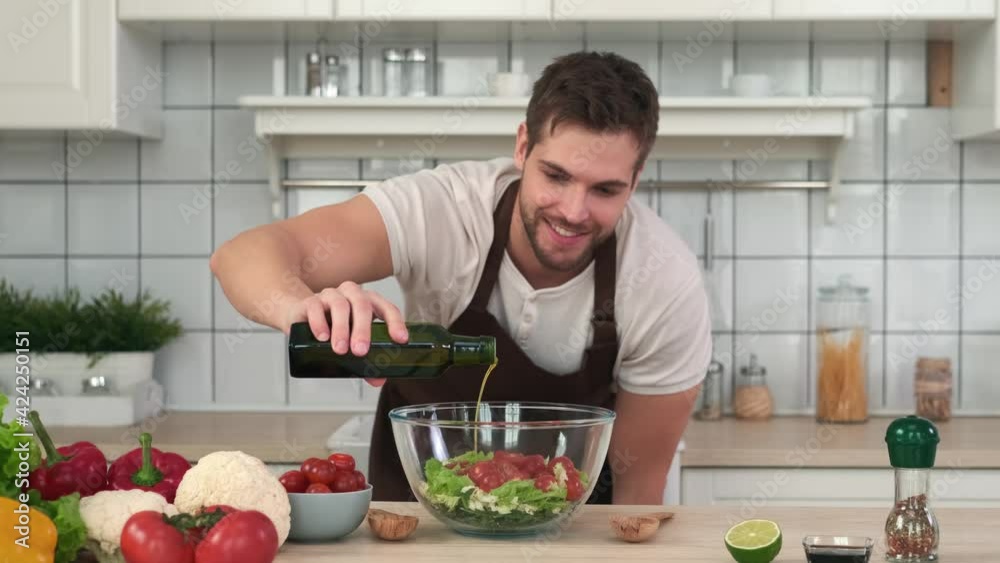 Vegan Cooking, Male Chef, Healthy Eating, Food Delivery. Male chef adding olive oil to vegan salad while standing in kitchen at home Vegan Cooking, Male Chef, Healthy Eating, Food Delivery. Male chef adding olive oil to vegan salad while standing in kitchen at home