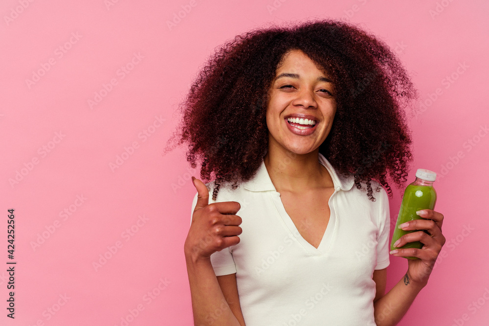 Young african american woman drinking a healthy smoothie isolated on pink background smiling and raising thumb up Young african american woman drinking a healthy smoothie isolated on pink background smiling and raising thumb up