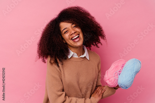Young african american woman holding a sewing threads isolated on pink background laughing and having fun.