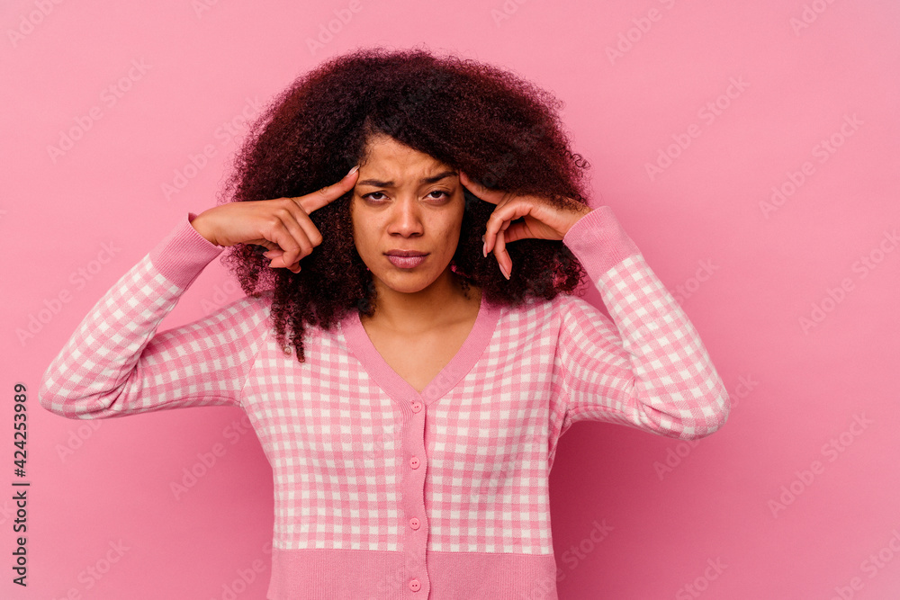 Young african american woman isolated on pink background focused on a task, keeping forefingers pointing head. Young african american woman isolated on pink background focused on a task, keeping forefingers pointing head.