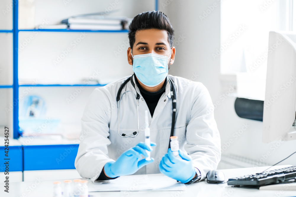 Portrait of a doctor in a protective mask with a vaccine and injections in his hands, modern medicine, internship in a modern hospital