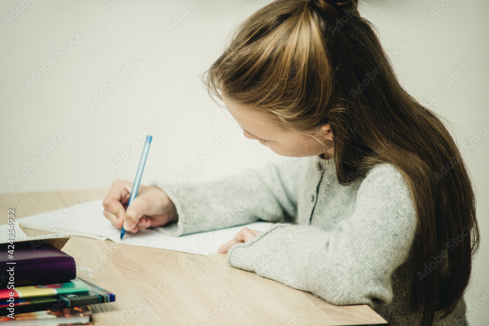 teen girl writing at the table on a white background teen girl writing at the table on a white background