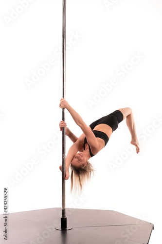 Slim girl performing acrobatic exercise on pole