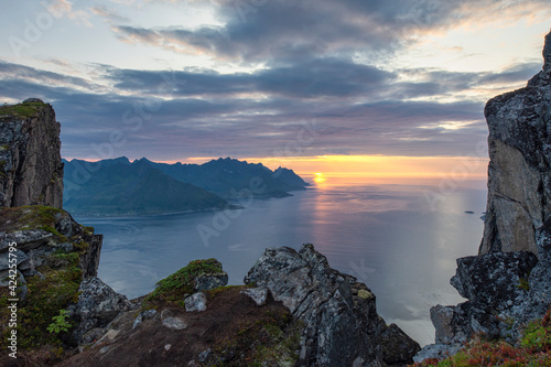 Amazing sunset over calm waters of Norwegian Sea. Senjahopen in the far distance. Mountain cliffs at foreground. Tourism, travel concept. Background. Copy space. photo