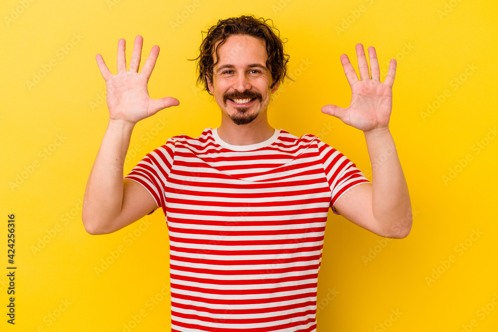 Young caucasian man isolated on yellow background showing number ten with hands. Young caucasian man isolated on yellow background showing number ten with hands.