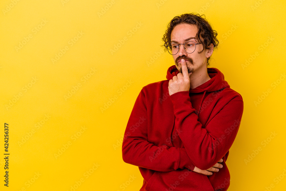 Young caucasian man isolated on yellow background looking sideways with doubtful and skeptical expression. Young caucasian man isolated on yellow background looking sideways with doubtful and skeptical expression.