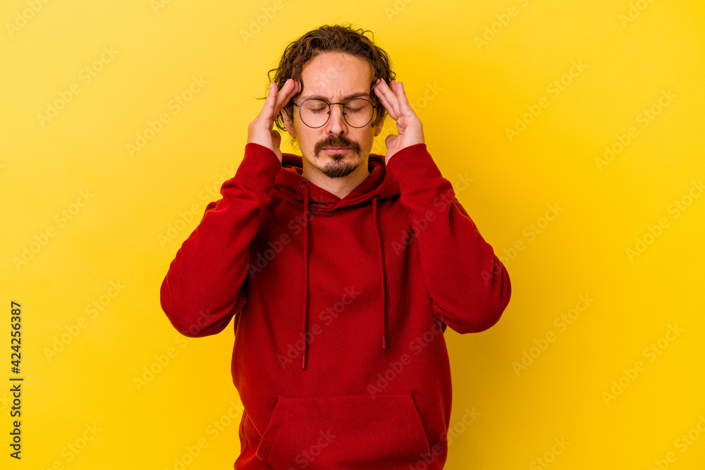 Young caucasian man isolated on yellow background touching temples and having headache. Young caucasian man isolated on yellow background touching temples and having headache.