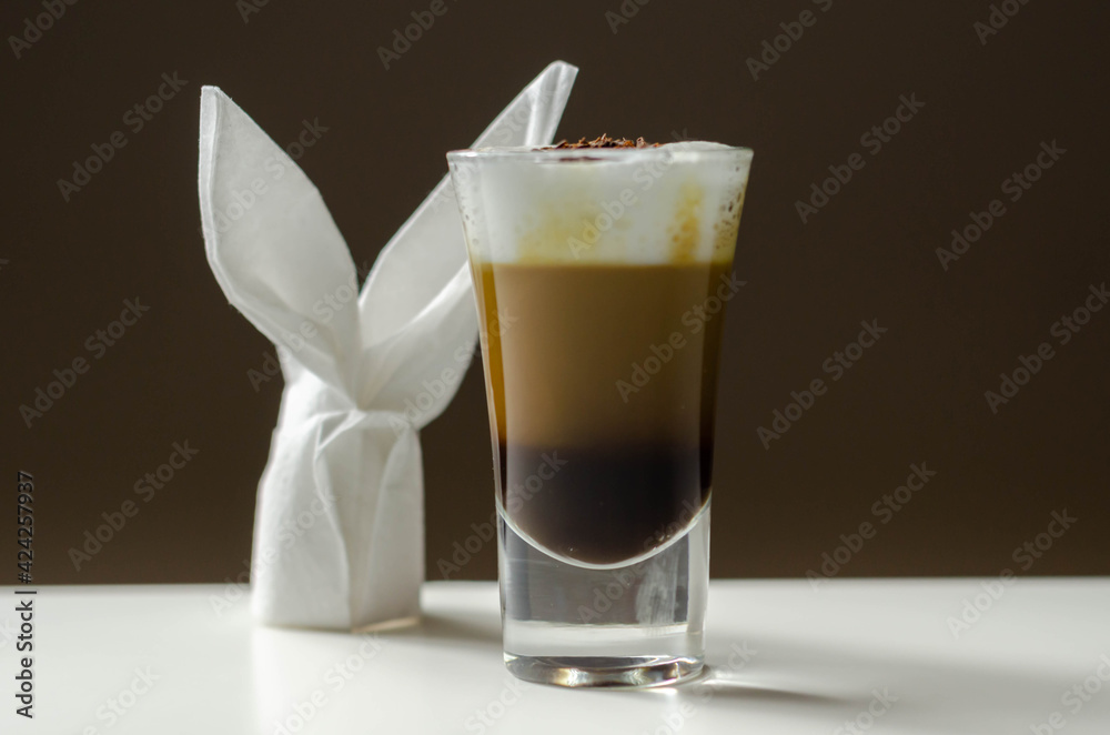 Coffee drink shot with a nutty note with fluffy milk foam, decorated with chocolate shavings, served with an Easter bunny-shaped napkin Coffee drink shot with a nutty note with fluffy milk foam, decorated with chocolate shavings, served with an Easter bunny-shaped napkin