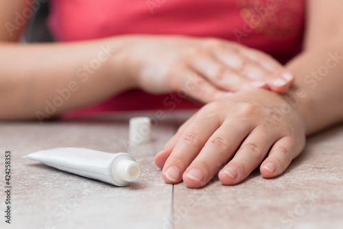 Woman is applying a moisturizer cream on her hands or anesthetic gel close up.