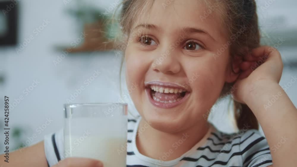 little girl child drinking milk. healthy eating a child eating breakfast kid dream concept. daughter girl in kitchen drinks yogurt milk kefir and licks her lips. positive kid smiling having breakfast little girl child drinking milk. healthy eating a child eating breakfast kid dream concept. daughter girl in kitchen drinks yogurt milk kefir and licks her lips. positive kid smiling having breakfast