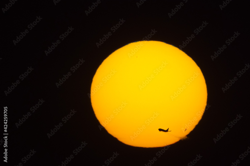 Sunset sun close up. Against the background of the sun, a plane takes off, a jet stream is visible. Sunset sun close up. Against the background of the sun, a plane takes off, a jet stream is visible.