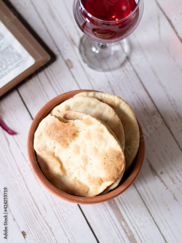 Unleavened bread matzo matza flatbread with a red wine glass and Holy Bible on wooden background. God Holy Days festival exodus.