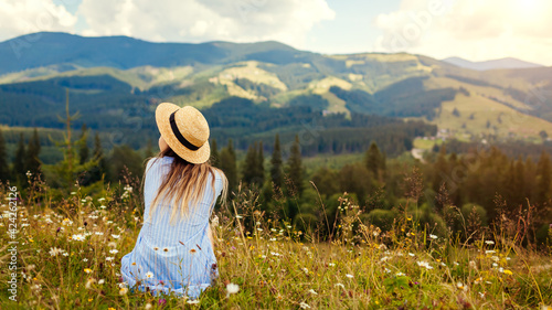 Traveling in spring Ukraine. Trip to Carpathian mountains. Woman traveler relaxing in flowers admiring landscape view