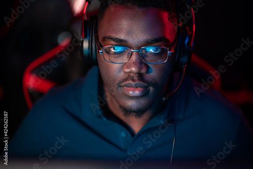 An african guy wearing headphones and glasses leads an online stream during the computer games championship