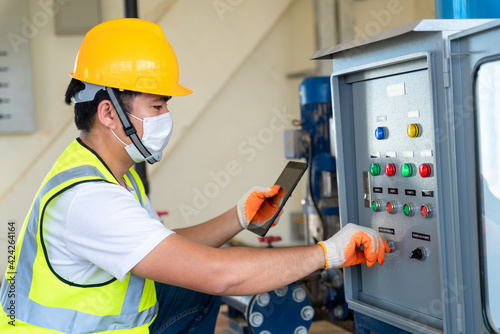 Asian engineer check panel broad of booster pump controller at water plant
