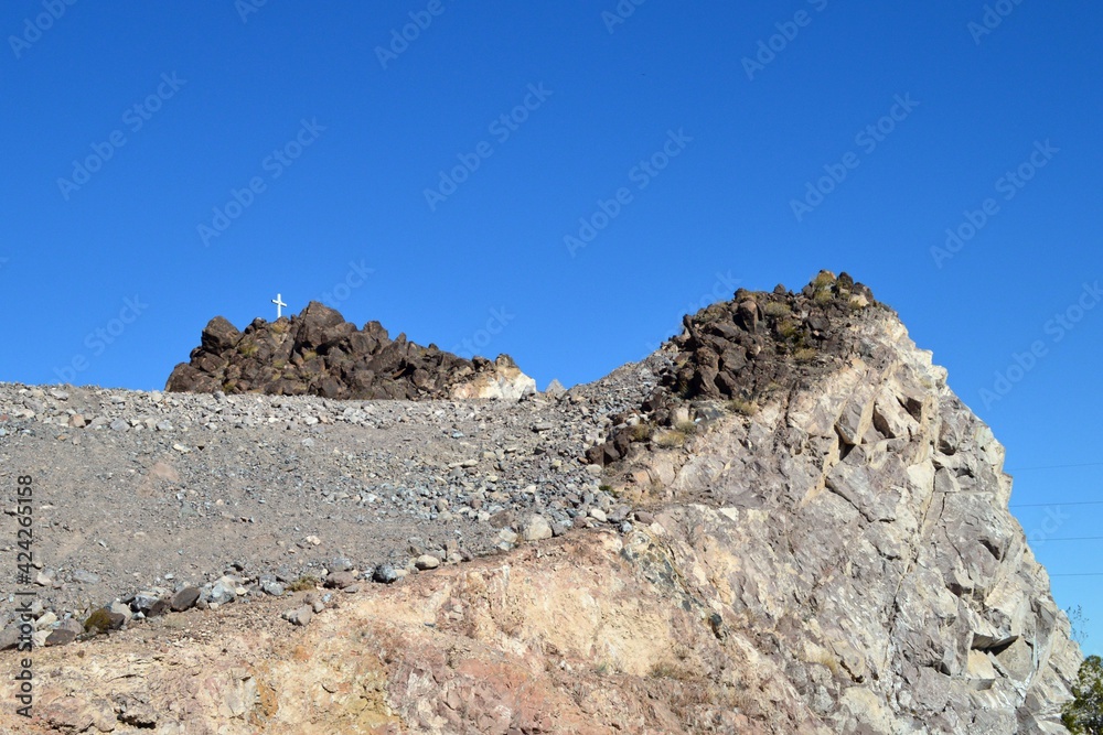 Lonely White Christan Cross on a stone mountaintop in Henderson, Clark County Nevada.