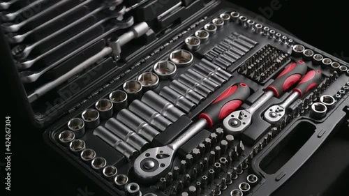 black tool box case opened by male worker hands in red clothes and using chrome tools