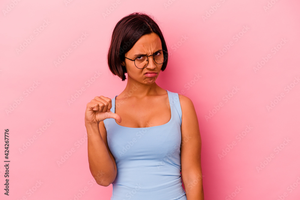 Young mixed race woman isolated on pink background showing thumb down and expressing dislike. Young mixed race woman isolated on pink background showing thumb down and expressing dislike.