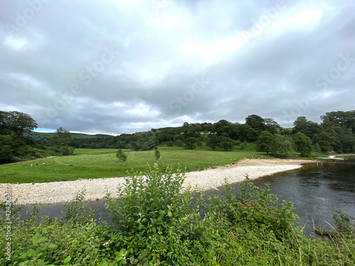 View of the banks of the, River Wharfe, on a cloudy day, near the B6160 road in, Burnsall, Skipton, UK photo