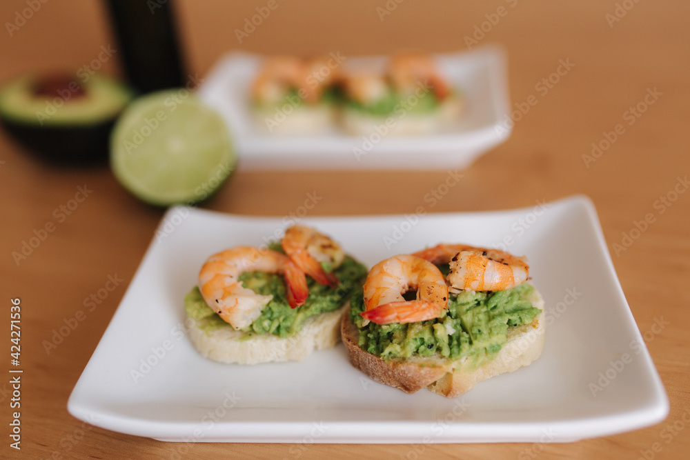 Healthy appetizer of bruschetta with guacamole shrimp closeup view. Fried shrimp and mashed avocado on a toasted bread
