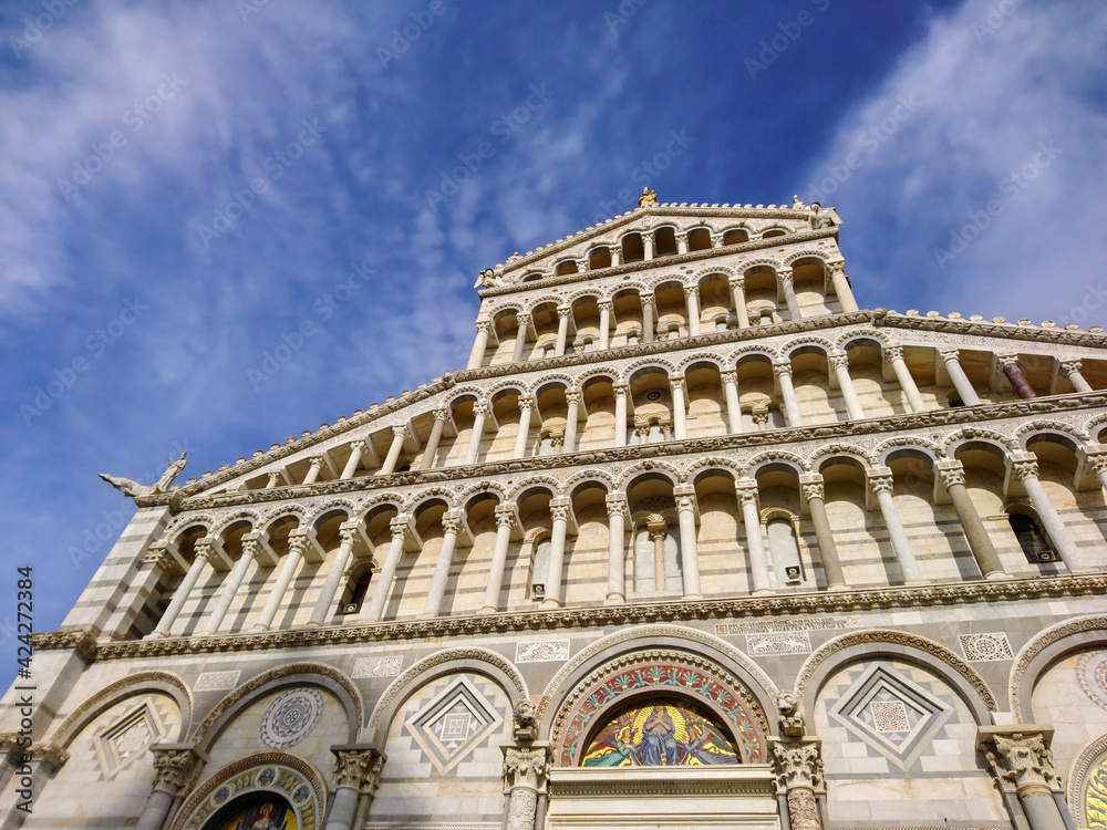 Cathedral of Pisa close view of grand marble-striped cathedral entrance facade on blue sky background. Travel Italy, famous places