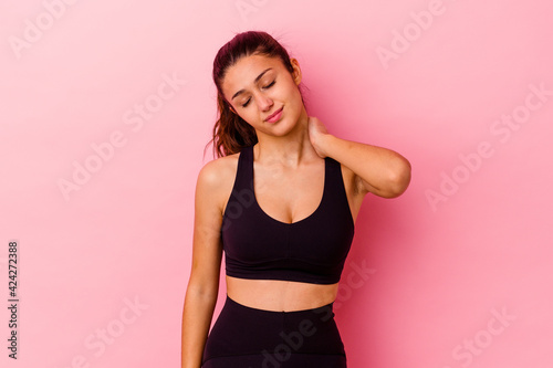 Fototapeta Naklejka Na Ścianę i Meble -  Young sport Indian woman isolated on pink background suffering neck pain due to sedentary lifestyle.